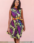 The model is wearing yellow-green dress with purple, black, white fish print 