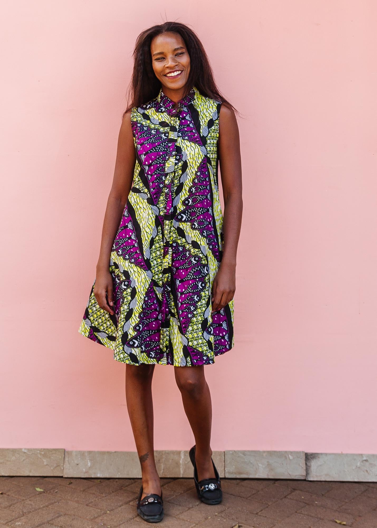 The model is wearing yellow-green dress with purple, black, white fish print 