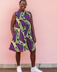 The model is wearing yellow-green dress with purple, black, white fish print 