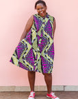 The model is wearing yellow-green dress with purple, black, white fish print 