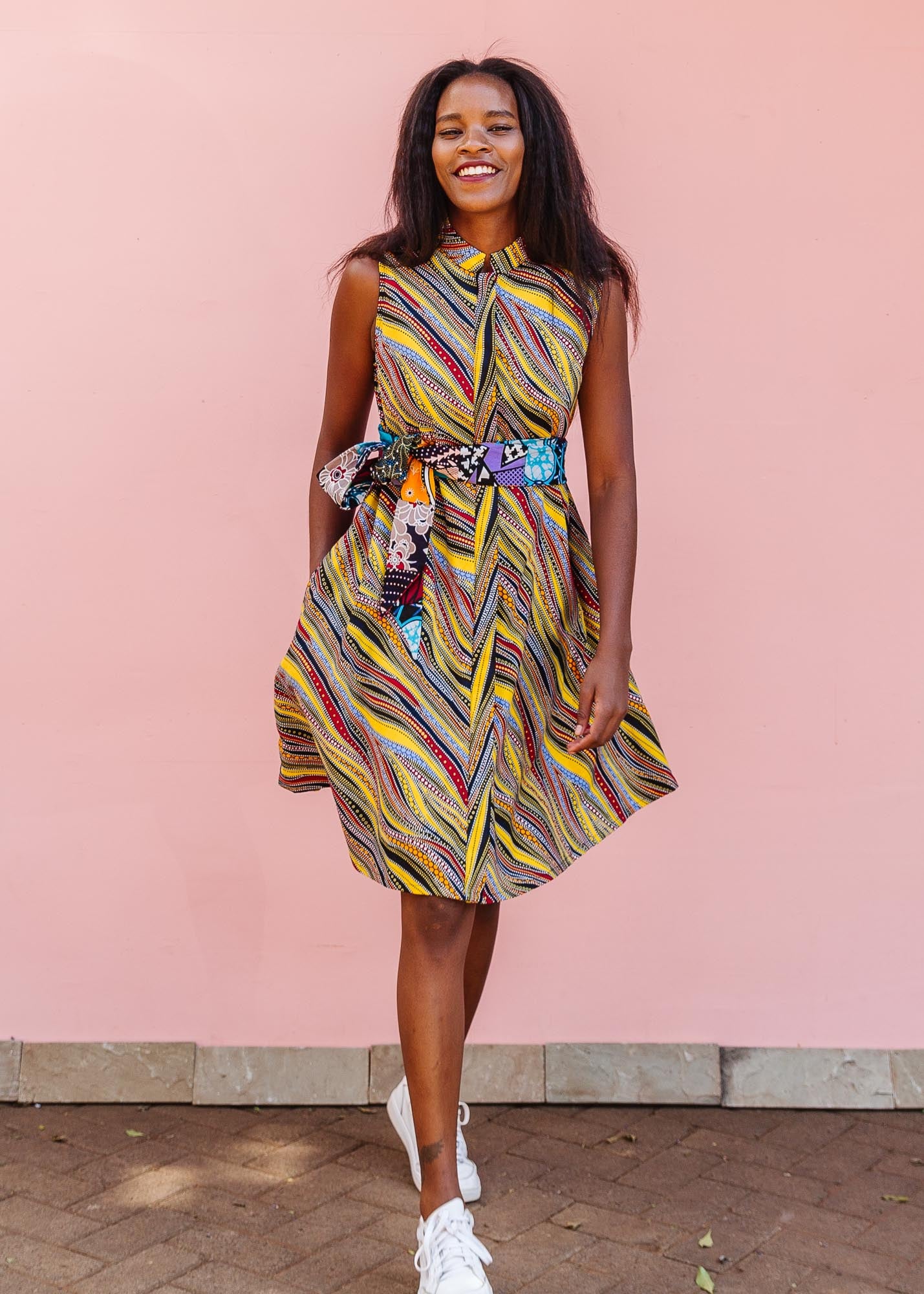 The model is wearing multi-colored abstract print dress