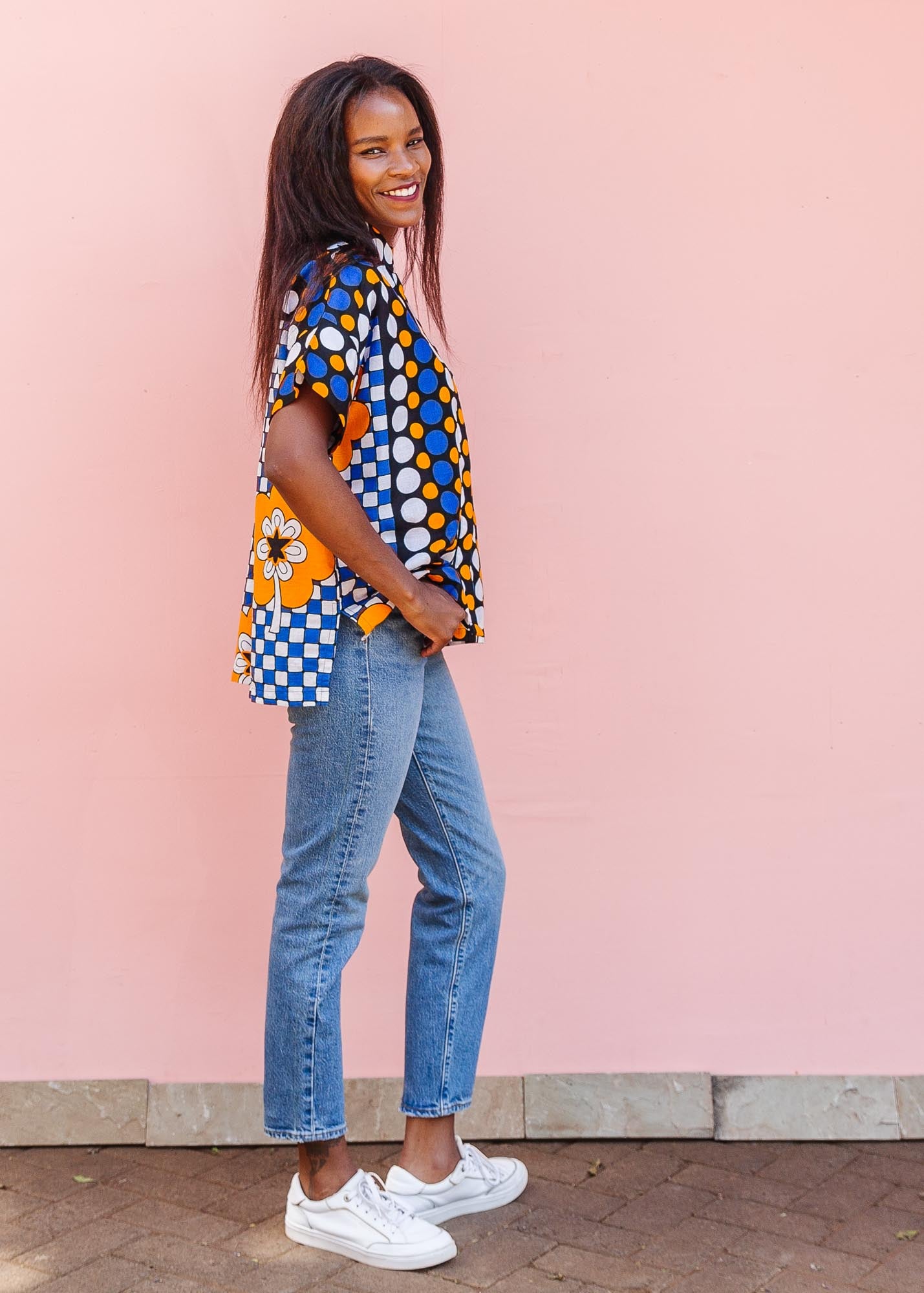 The model is wearing black, white, orange and blue mixed pattern kanga shirt