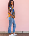 The model is wearing black, white, orange and blue mixed pattern kanga shirt