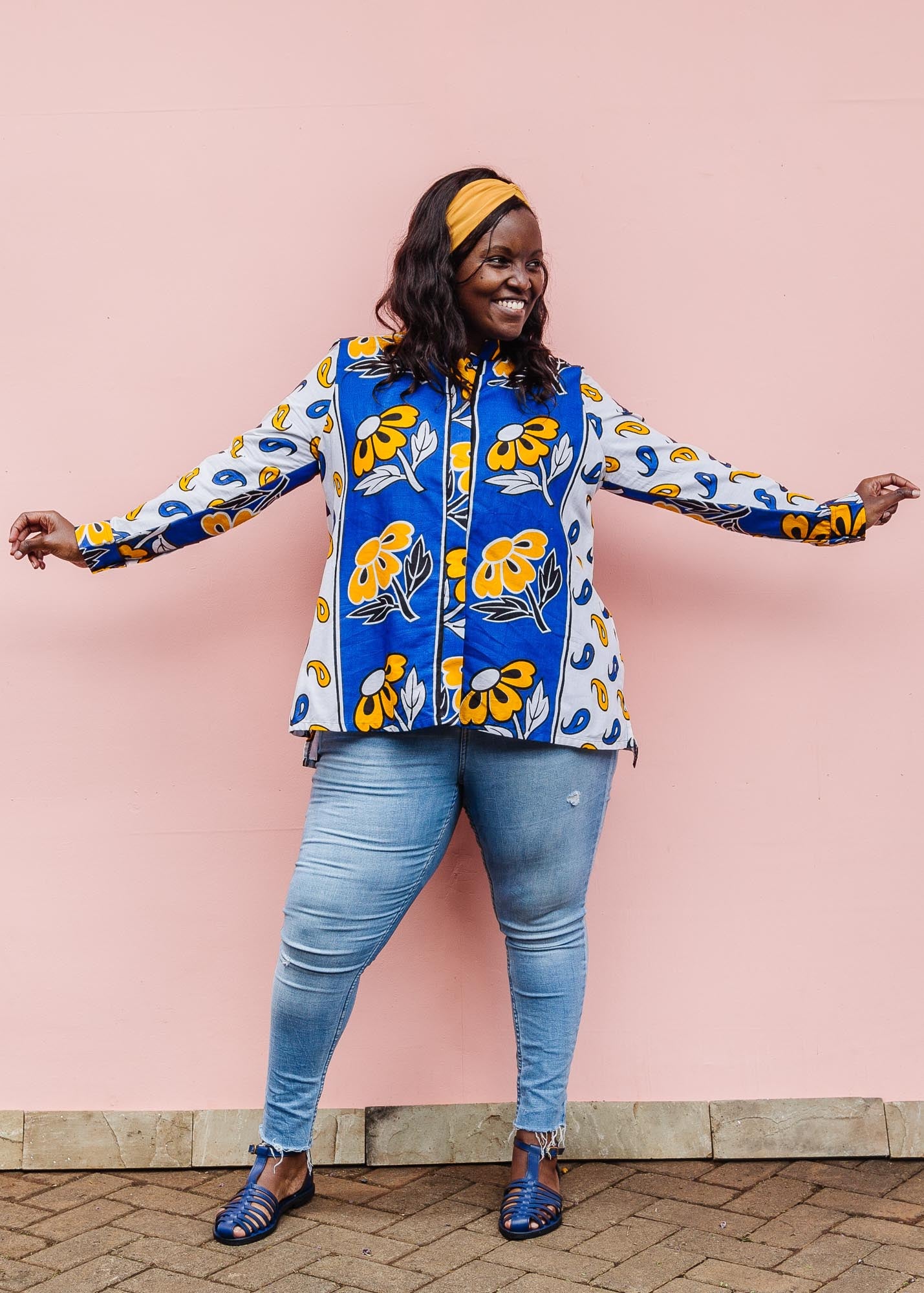 The model is wearing white, blue, black and orange mixed pattern long sleeved kanga shirt