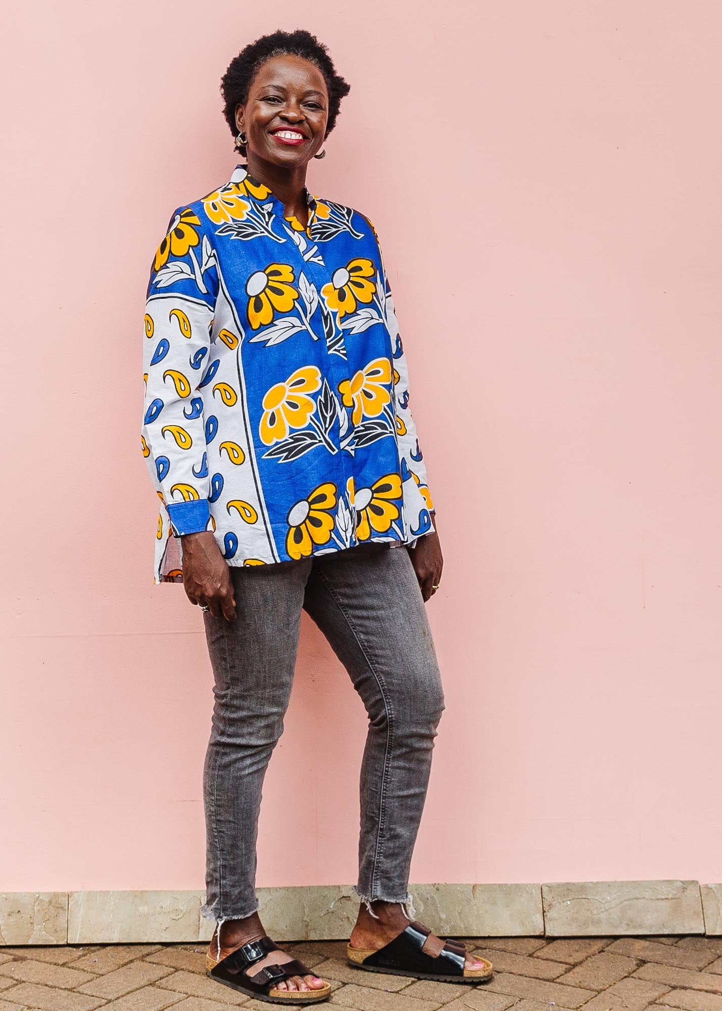 The model is wearing white, blue, black and orange mixed pattern long sleeved kanga shirt