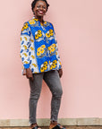 The model is wearing white, blue, black and orange mixed pattern long sleeved kanga shirt