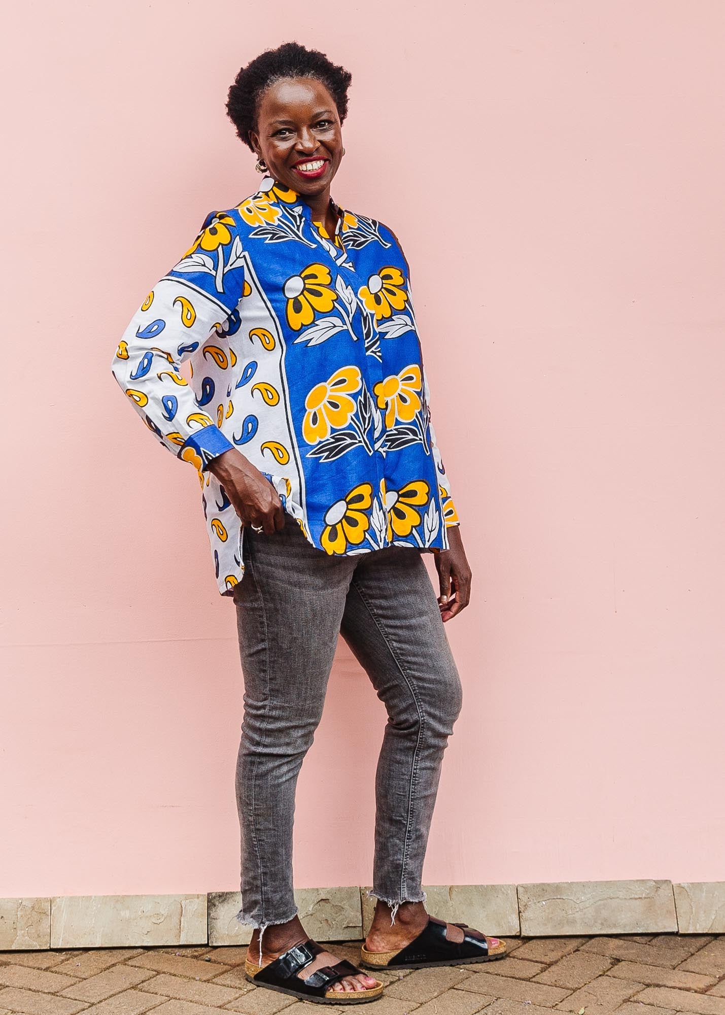 The model is wearing white, blue, black and orange mixed pattern long sleeved kanga shirt