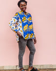 The model is wearing white, blue, black and orange mixed pattern long sleeved kanga shirt