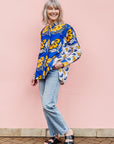 The model is wearing white, blue, black and orange mixed pattern long sleeved kanga shirt