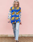 The model is wearing white, blue, black and orange mixed pattern long sleeved kanga shirt