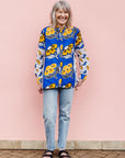 The model is wearing white, blue, black and orange mixed pattern long sleeved kanga shirt