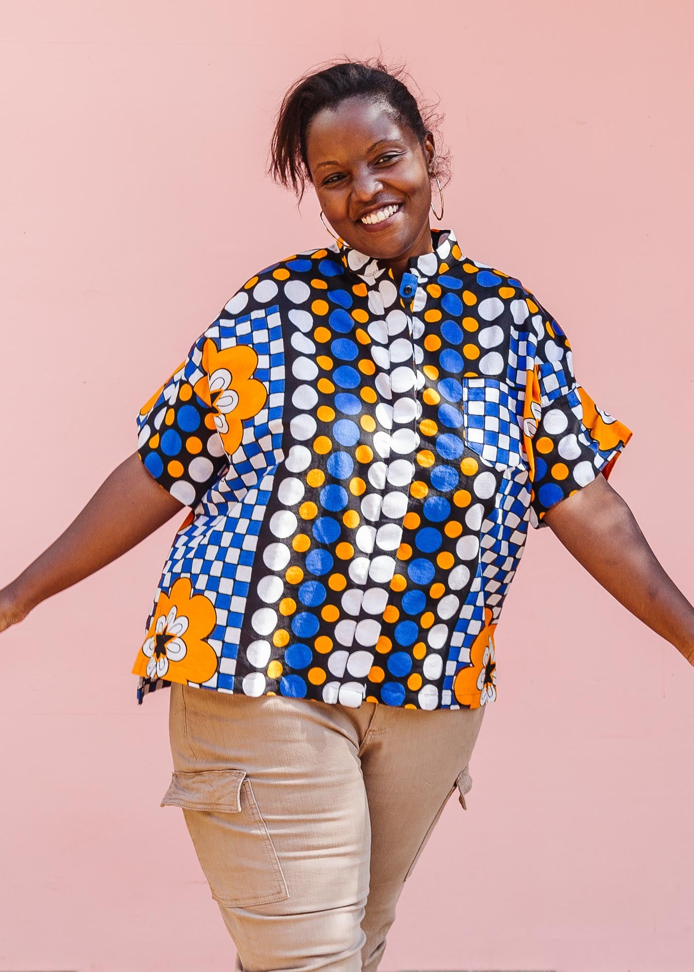 The model is wearing black, white, orange and blue mixed pattern kanga shirt