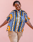 The model is wearing black, white, orange and blue mixed pattern kanga shirt