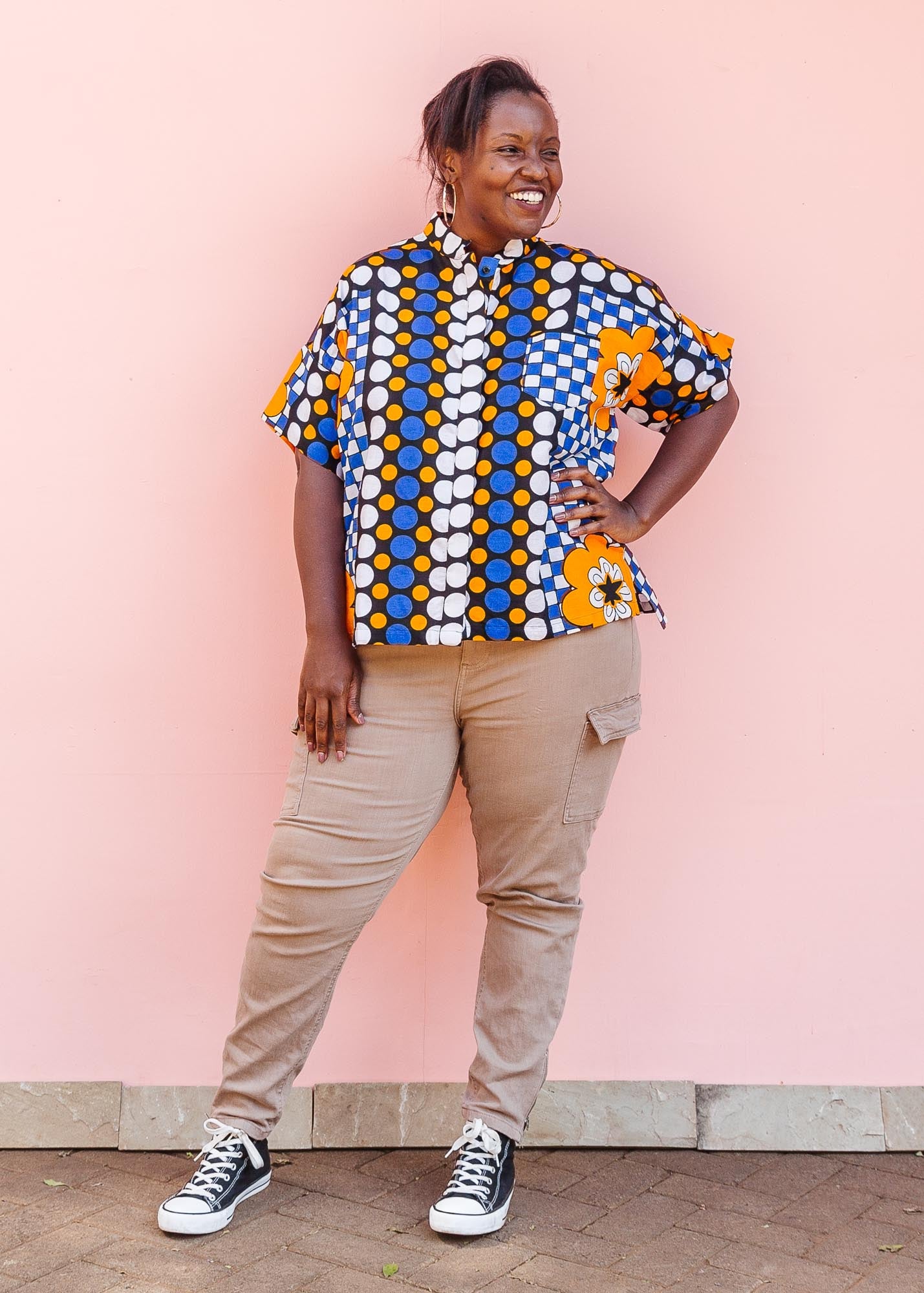 The model is wearing black, white, orange and blue mixed pattern kanga shirt