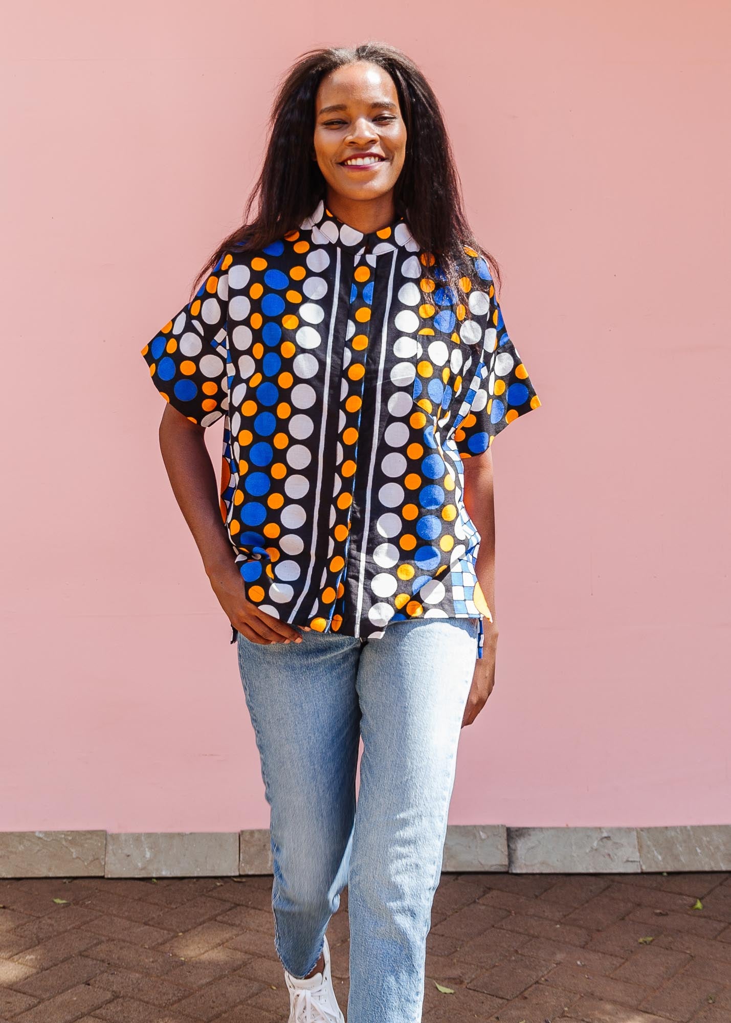 The model is wearing black, white, orange and blue mixed pattern kanga shirt