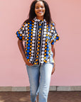 The model is wearing black, white, orange and blue mixed pattern kanga shirt