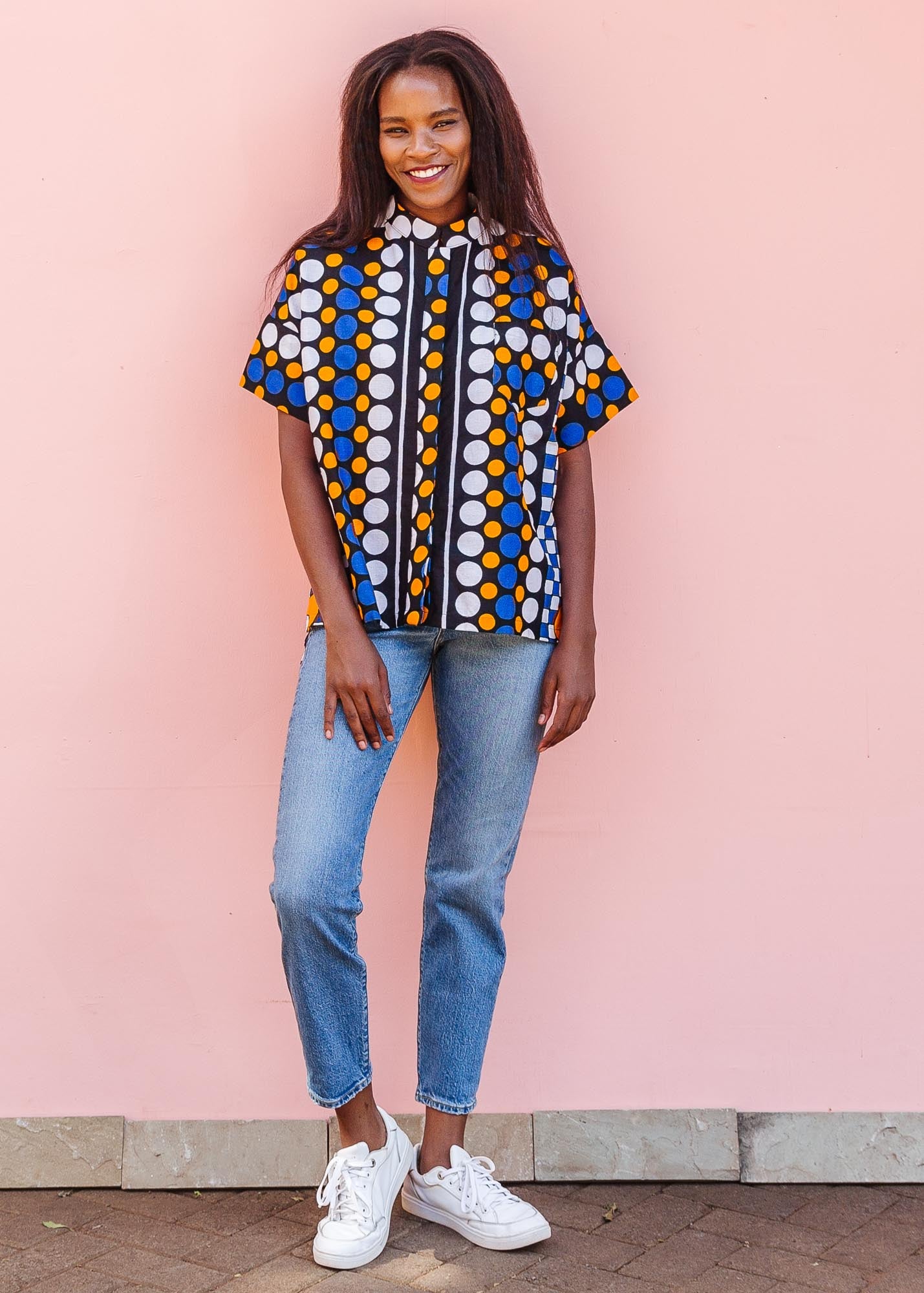 The model is wearing black, white, orange and blue mixed pattern kanga shirt