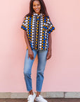 The model is wearing black, white, orange and blue mixed pattern kanga shirt