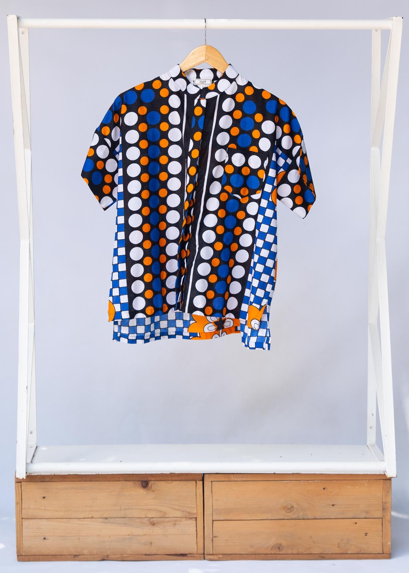 Display of black, white, orange and blue mixed pattern kanga shirt