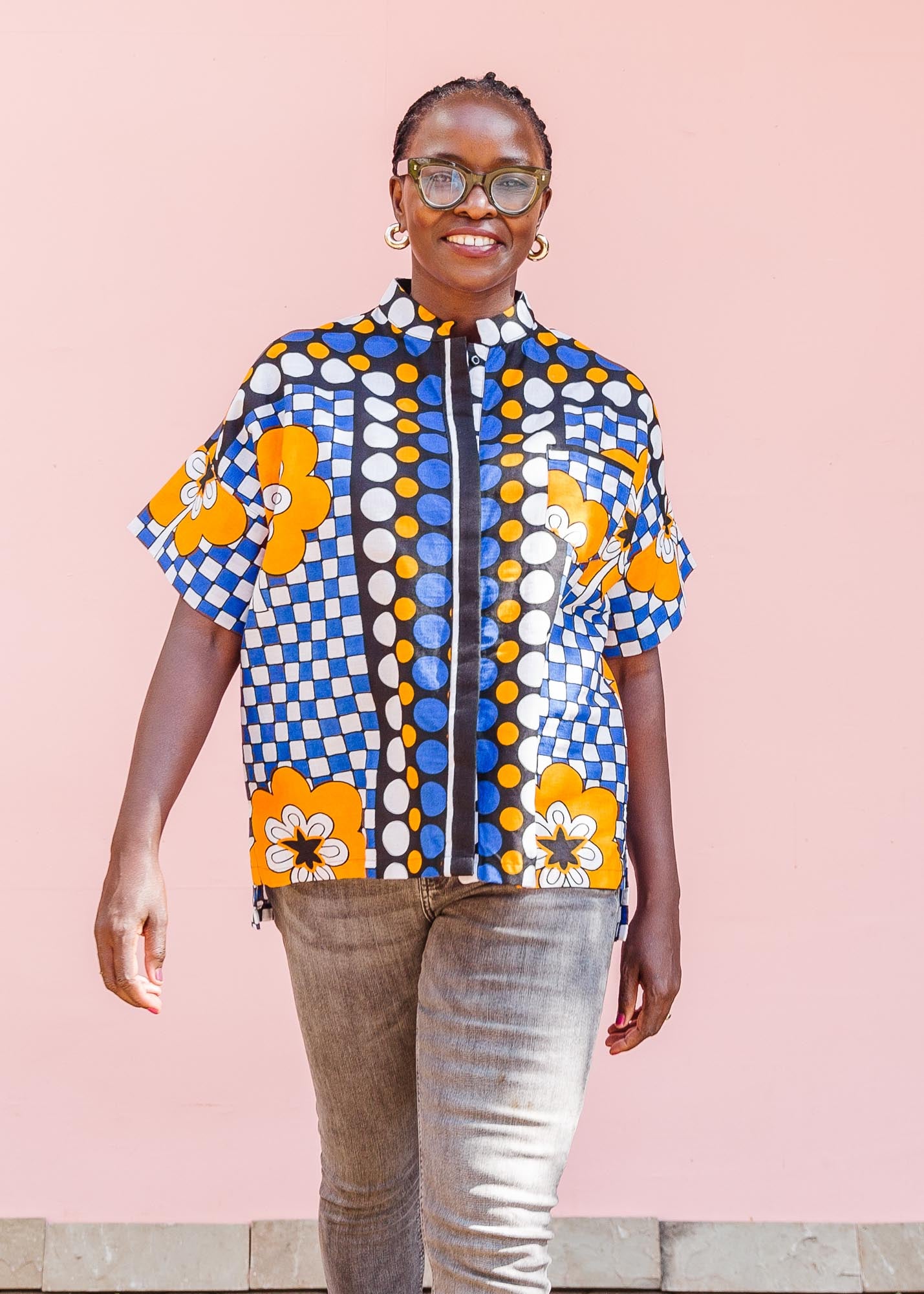 The model is wearing black, white, orange and blue mixed pattern kanga shirt