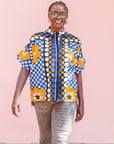 The model is wearing black, white, orange and blue mixed pattern kanga shirt