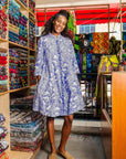 The model is wearing violet and white leaf print dress