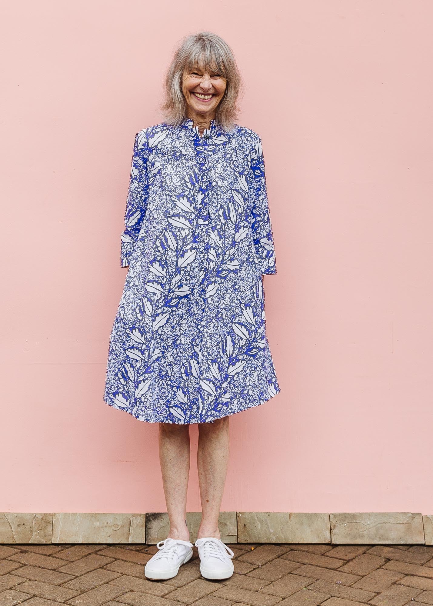 The model is wearing violet and white leaf print dress