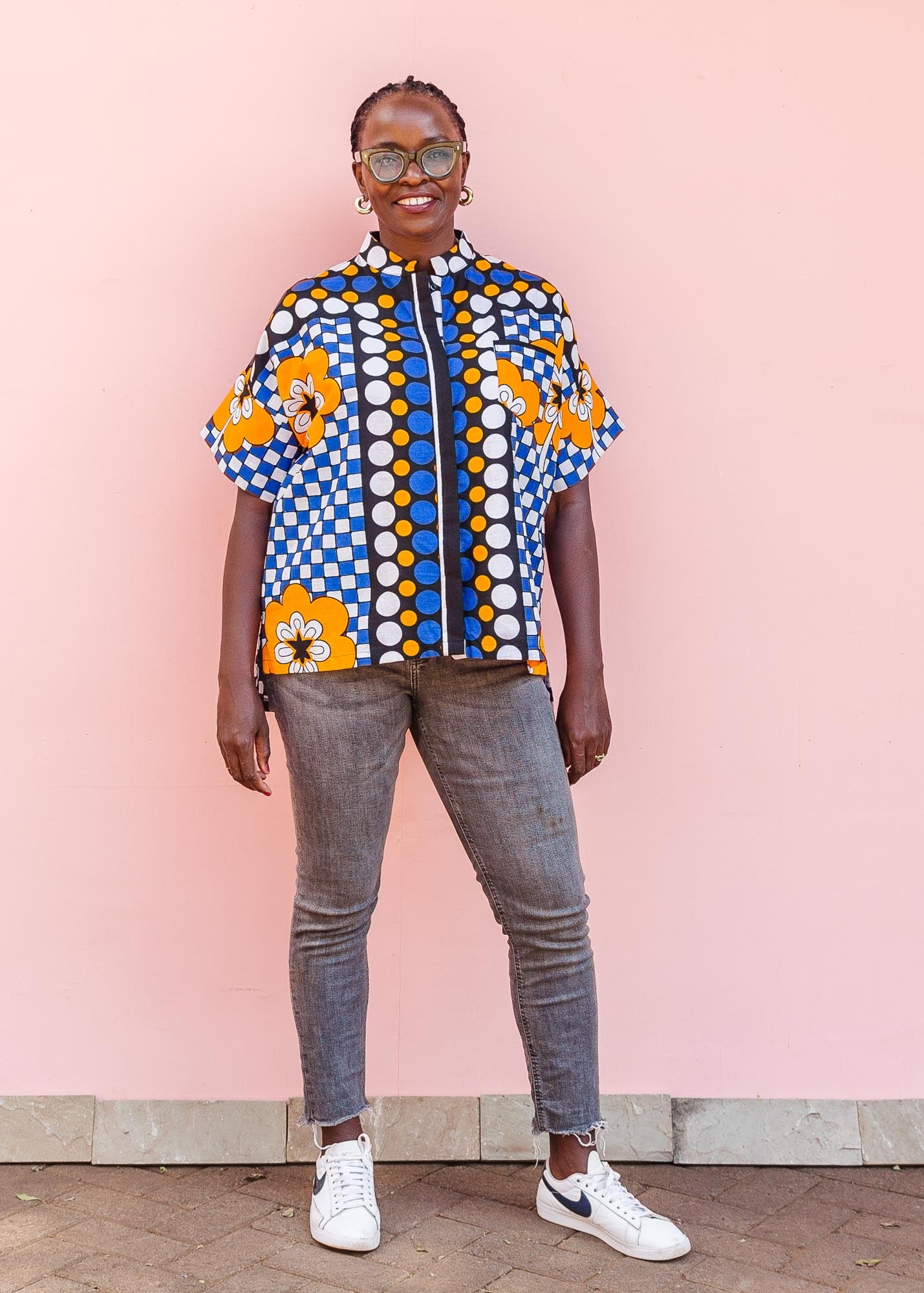 The model is wearing black, white, orange and blue mixed pattern kanga shirt