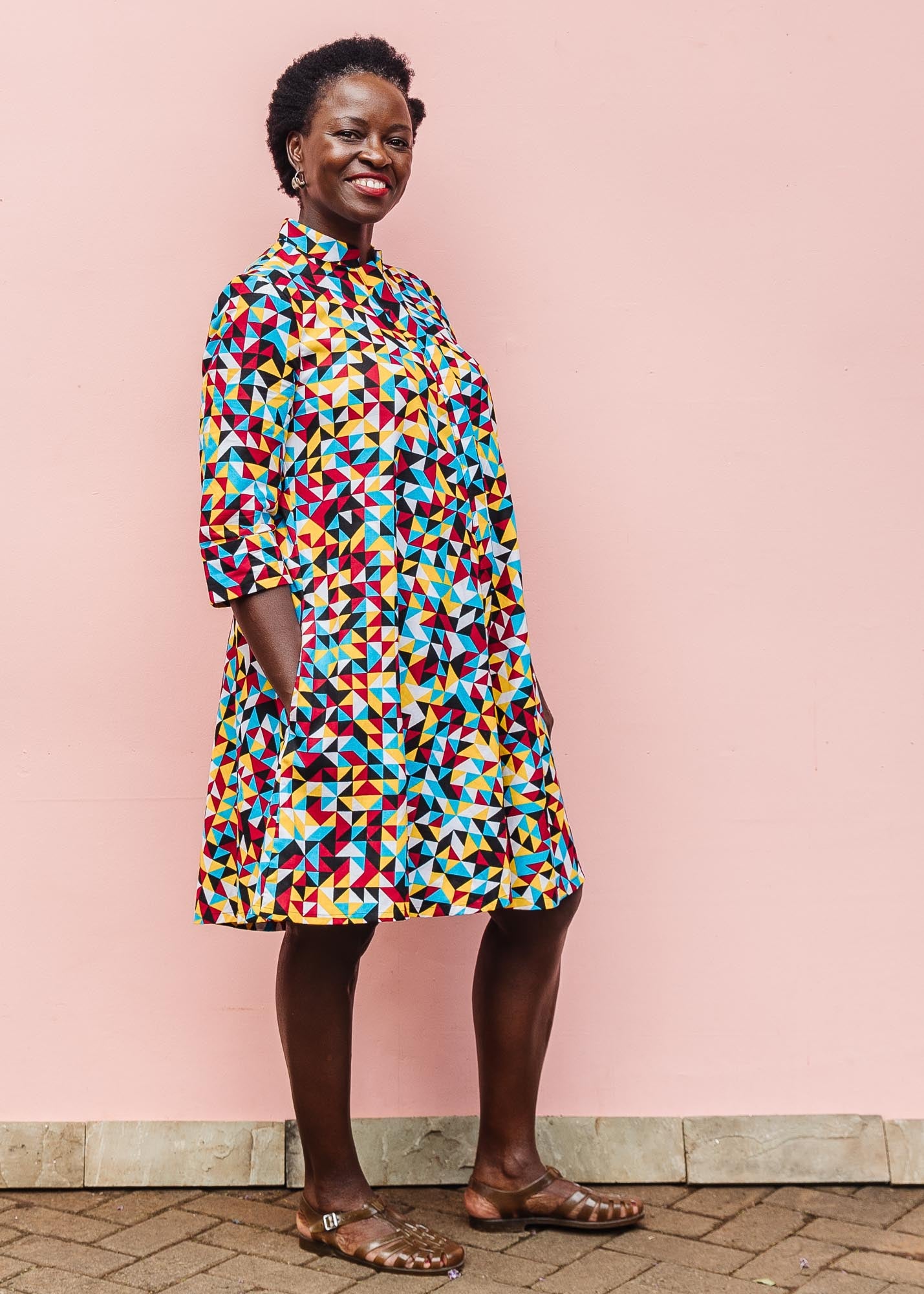 The model is wearing multi colored geometric print dress