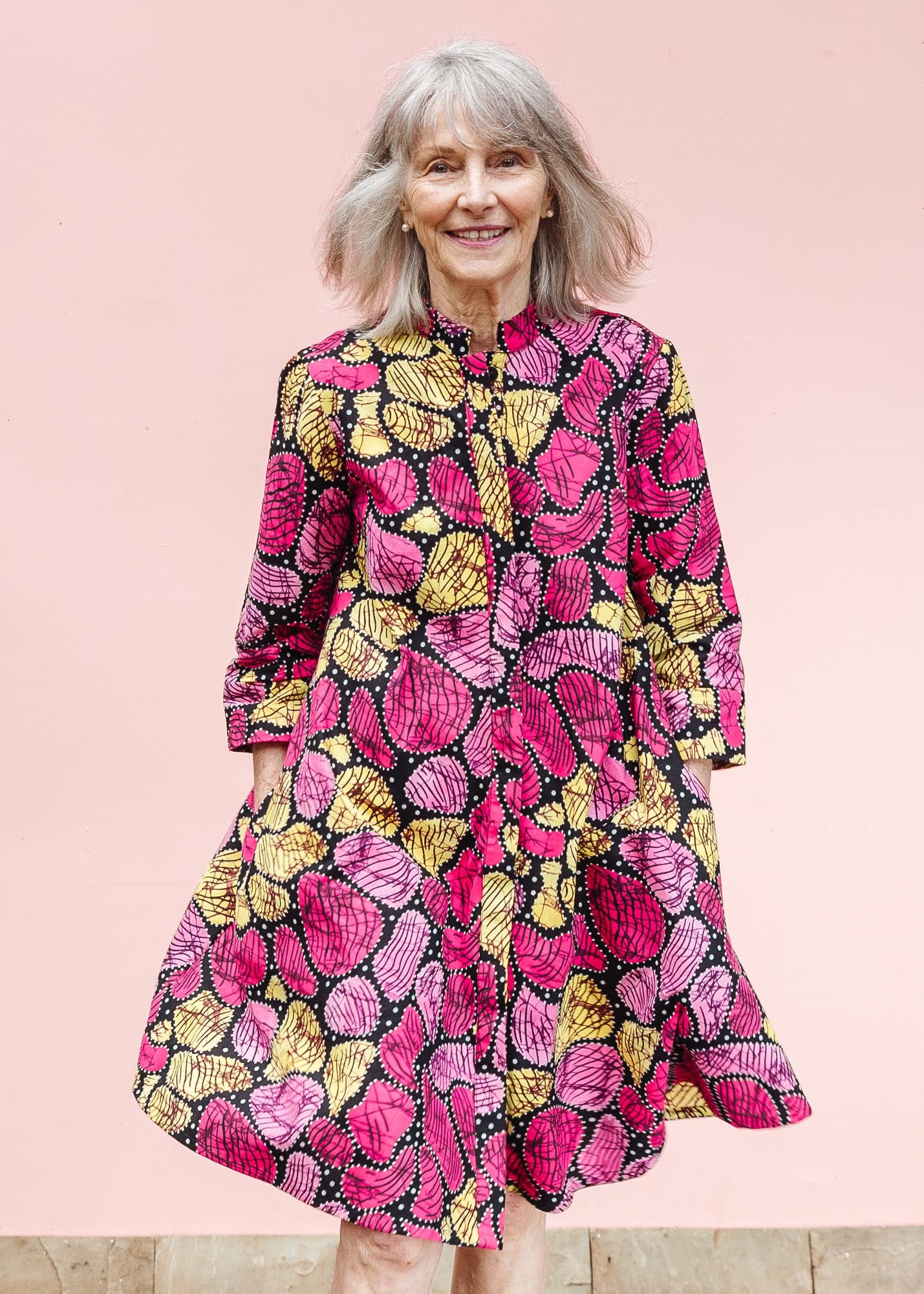 The model is wearing black, white, yellow, brown, pink, hot pink and purple bubble print dress