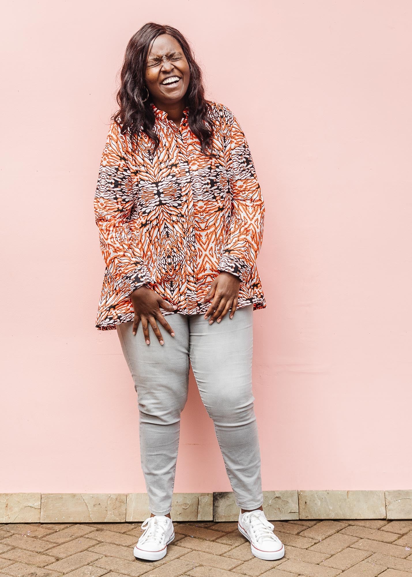 The model is wearing orange, black and white abstract print long sleeved shirt