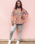 The model is wearing orange, black and white abstract print long sleeved shirt