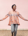 The model is wearing orange, black and white abstract print long sleeved shirt