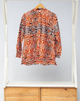 Display of orange, black and white abstract print long sleeved shirt