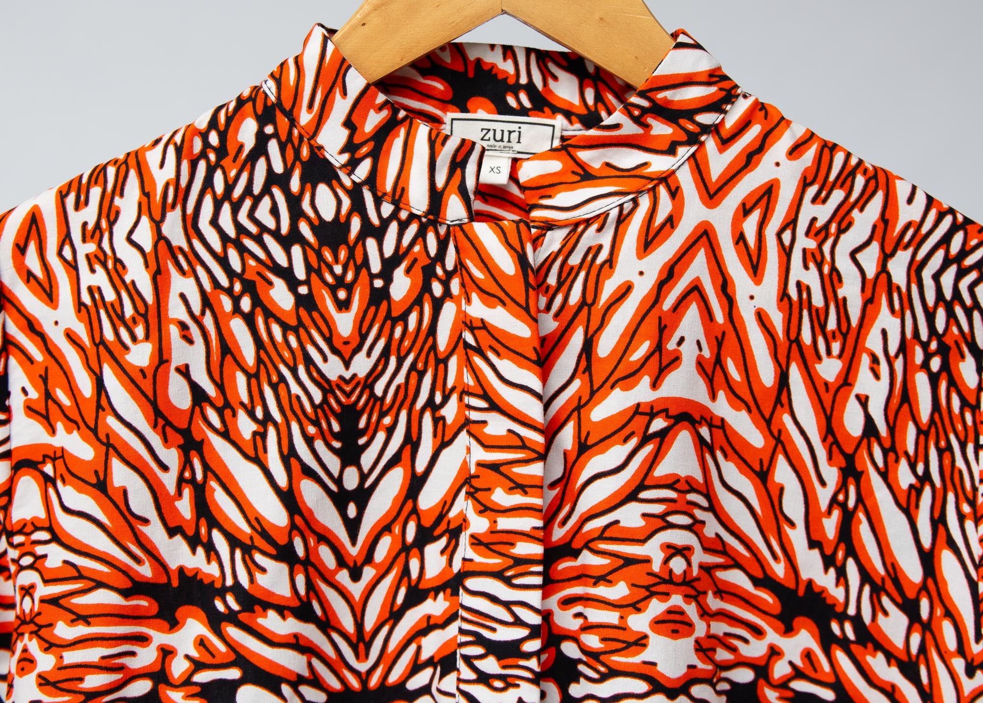 Display of orange, black and white abstract print long sleeved shirt