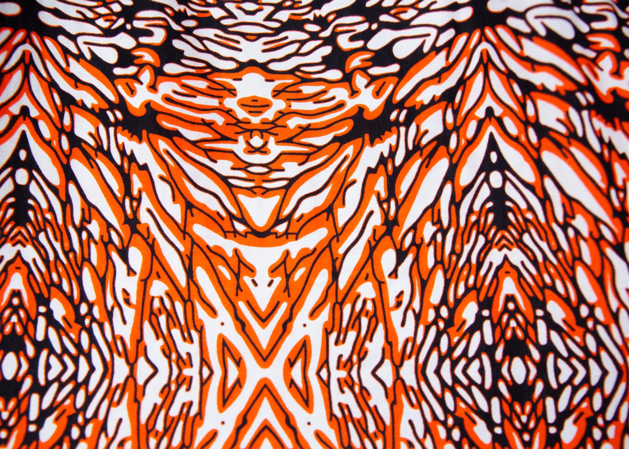 Close up display of orange, black and white abstract print long sleeved shirt