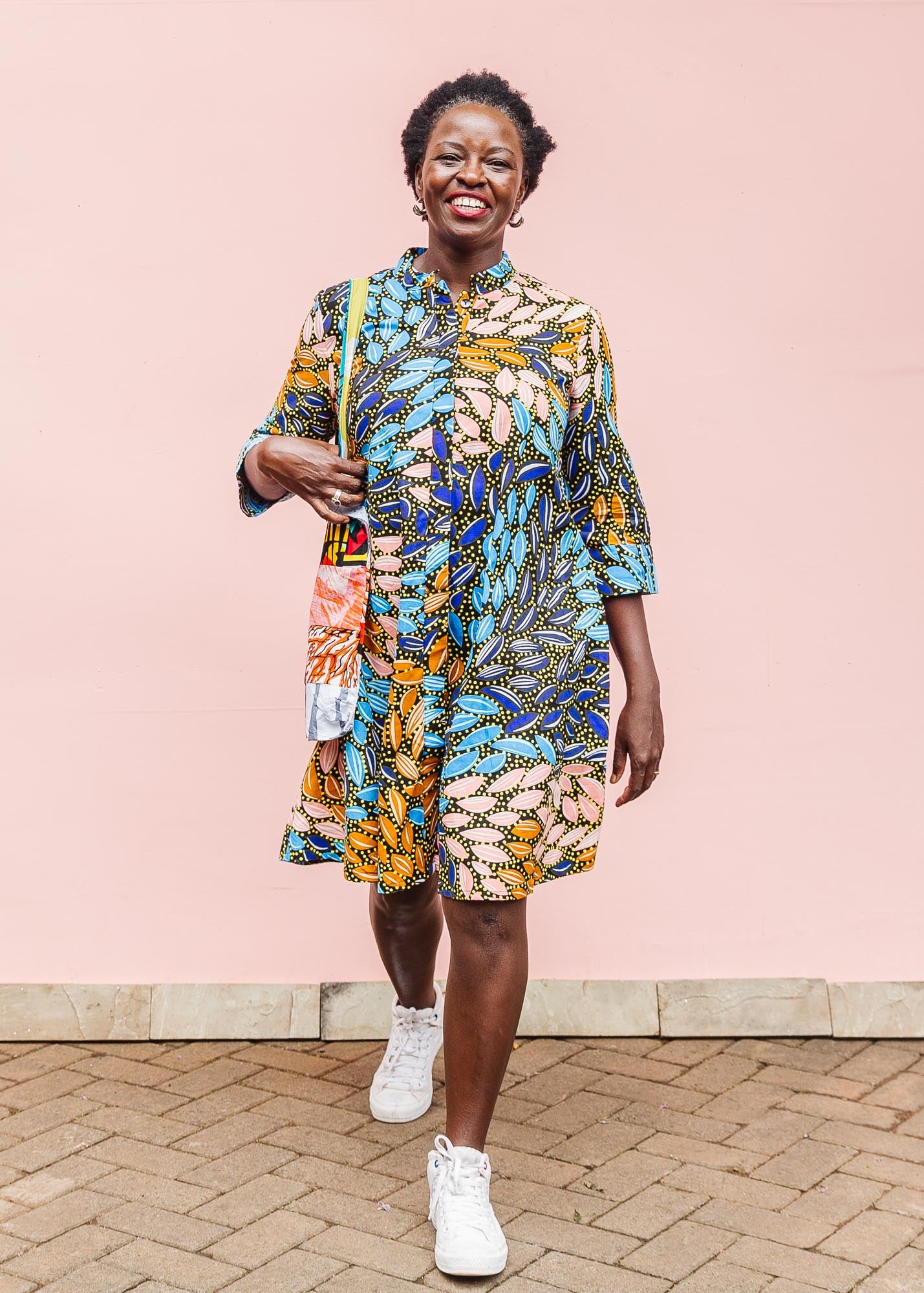 The model is wearing black dress with yellow dots and brown, blues, peach leaves.