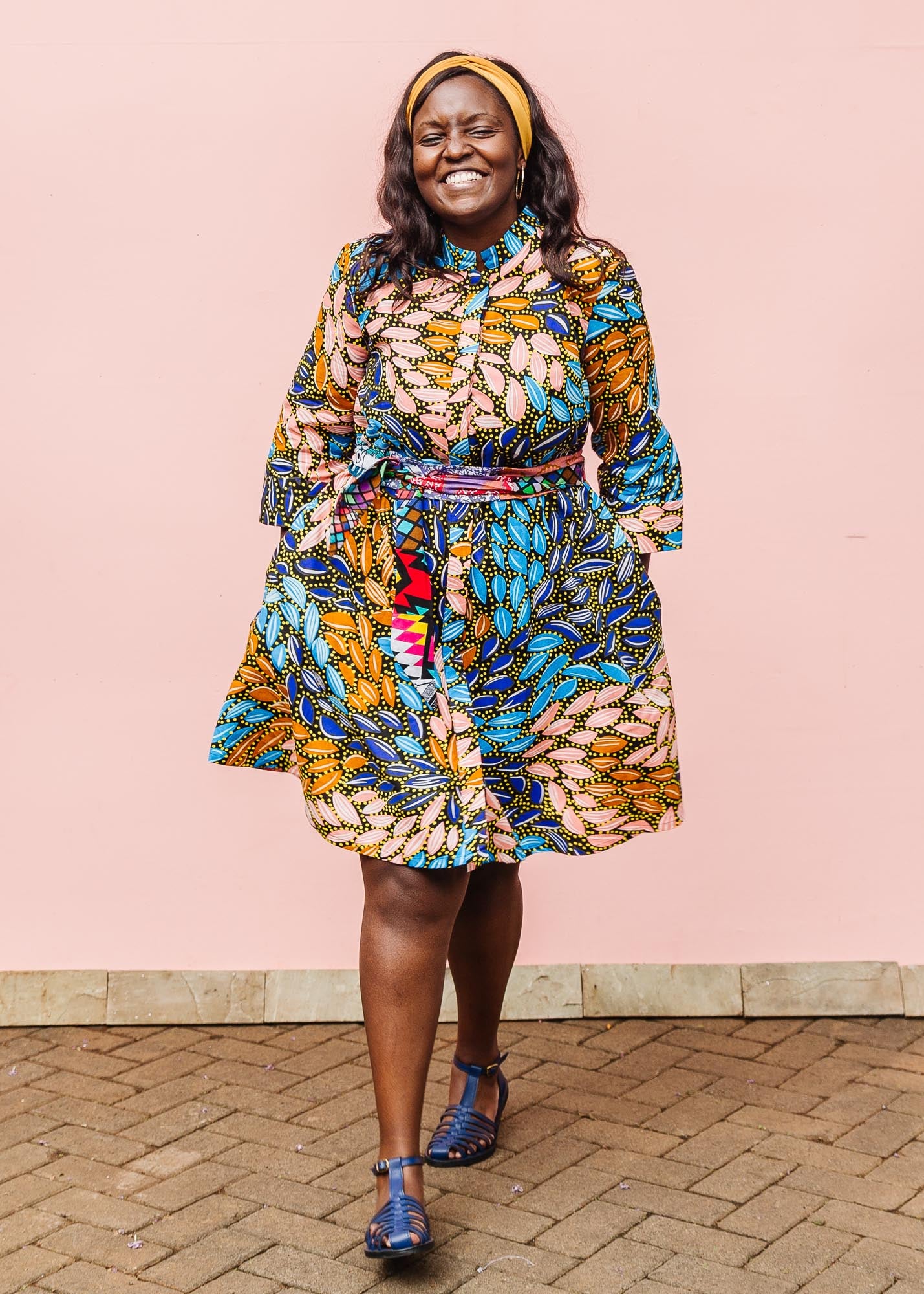 The model is wearing black dress with yellow dots and brown, blues, peach leaves.