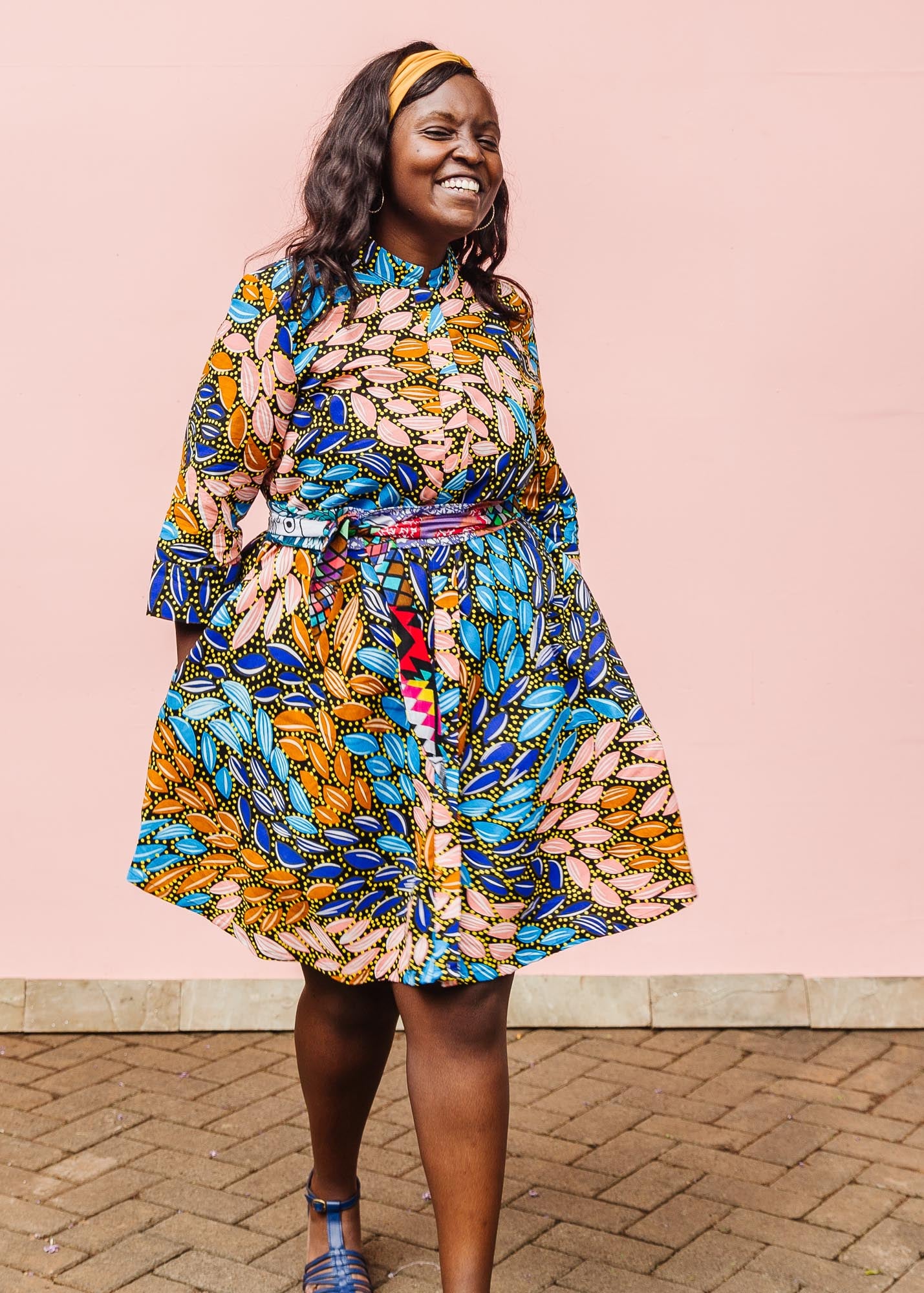 The model is wearing black dress with yellow dots and brown, blues, peach leaves.