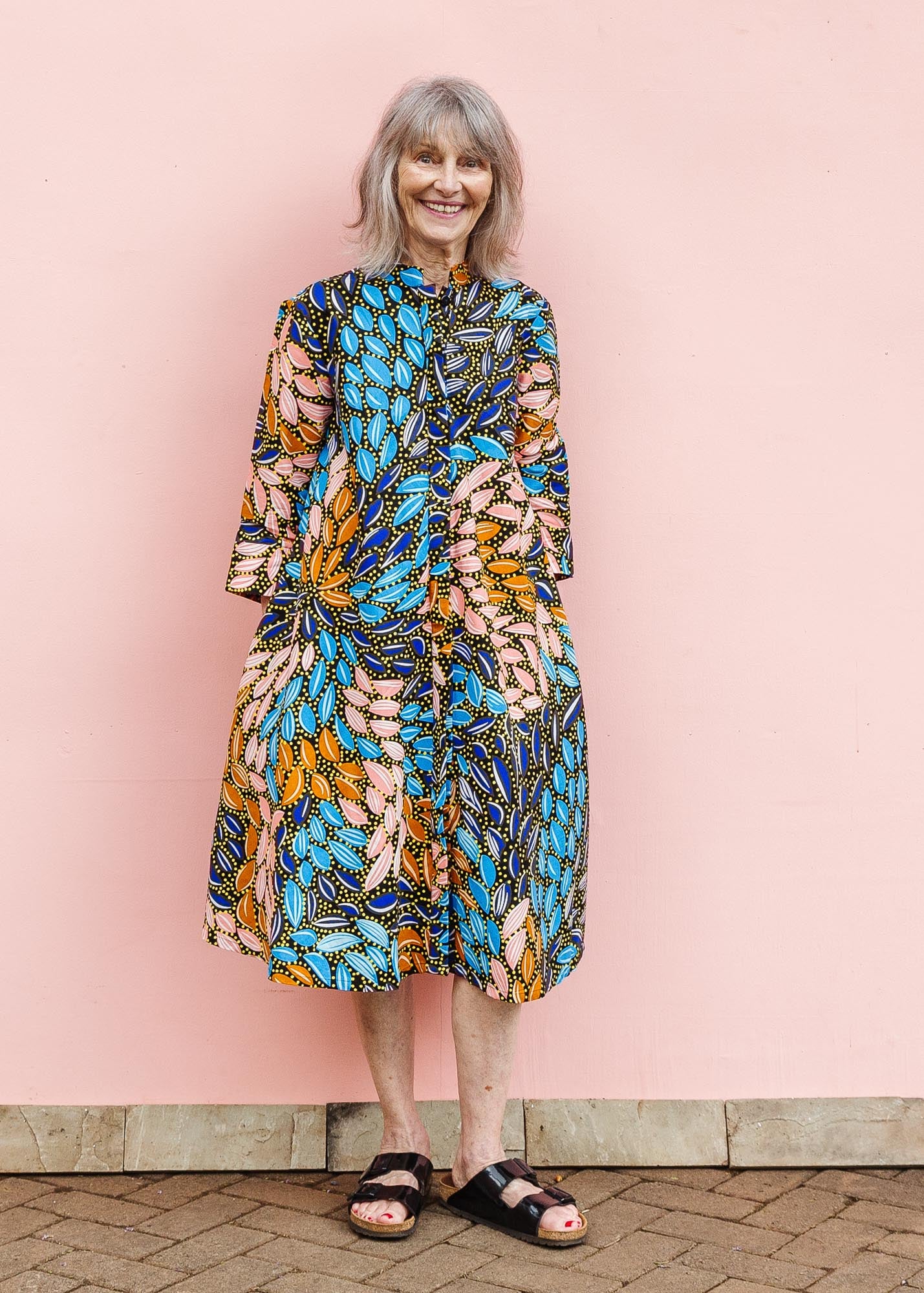 The model is wearing black dress with yellow dots and brown, blues, peach leaves.