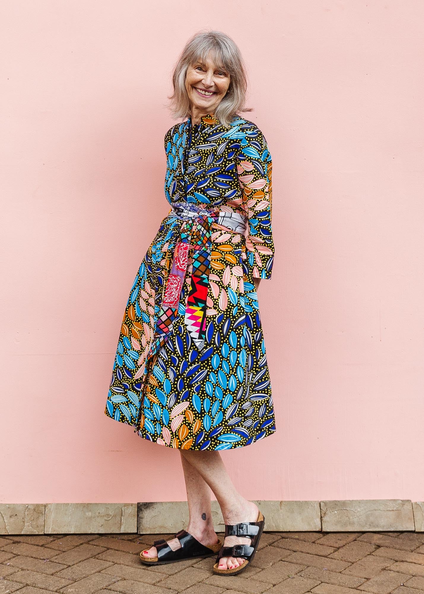 The model is wearing black dress with yellow dots and brown, blues, peach leaves.