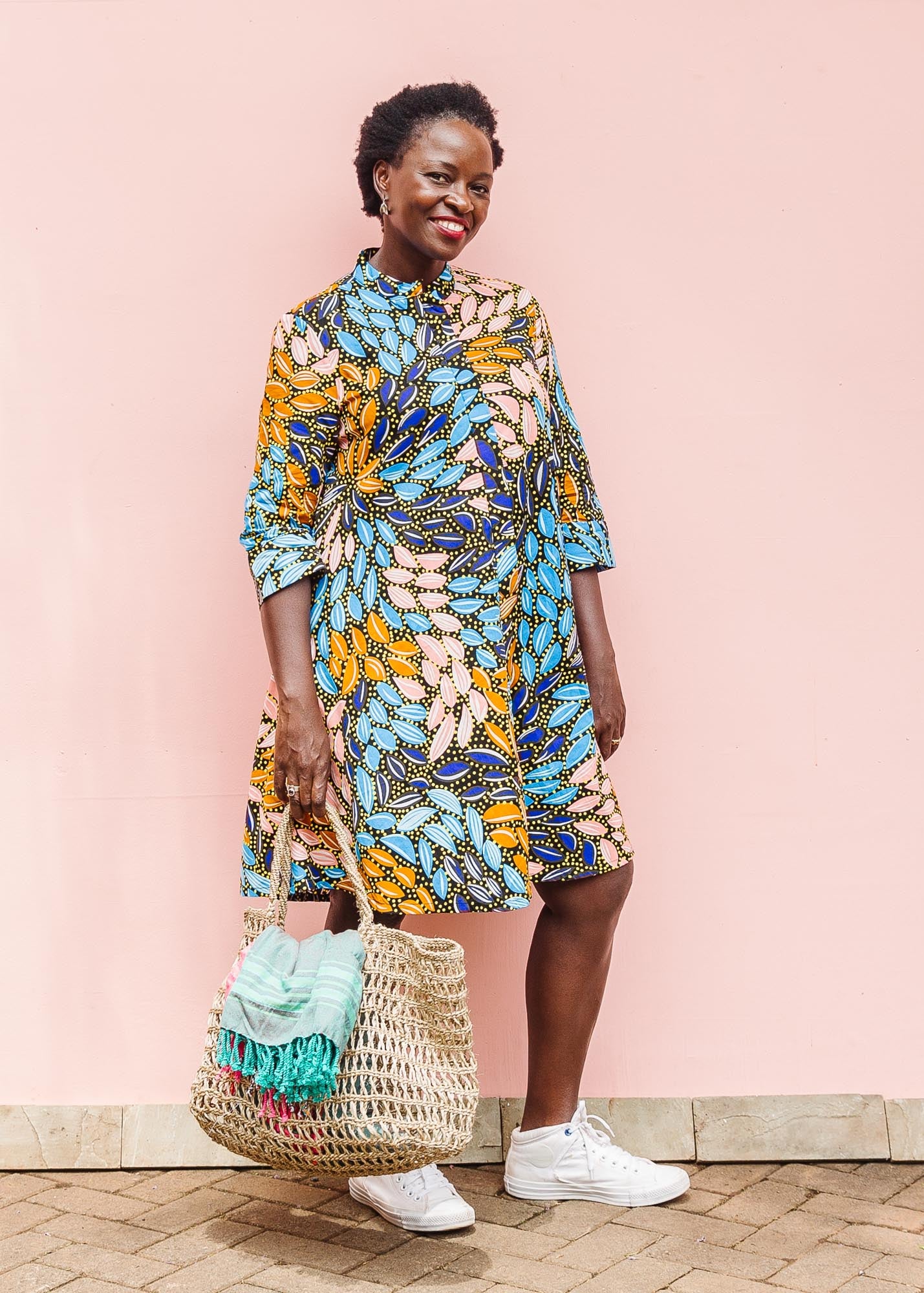 The model is wearing black dress with yellow dots and brown, blues, peach leaves.