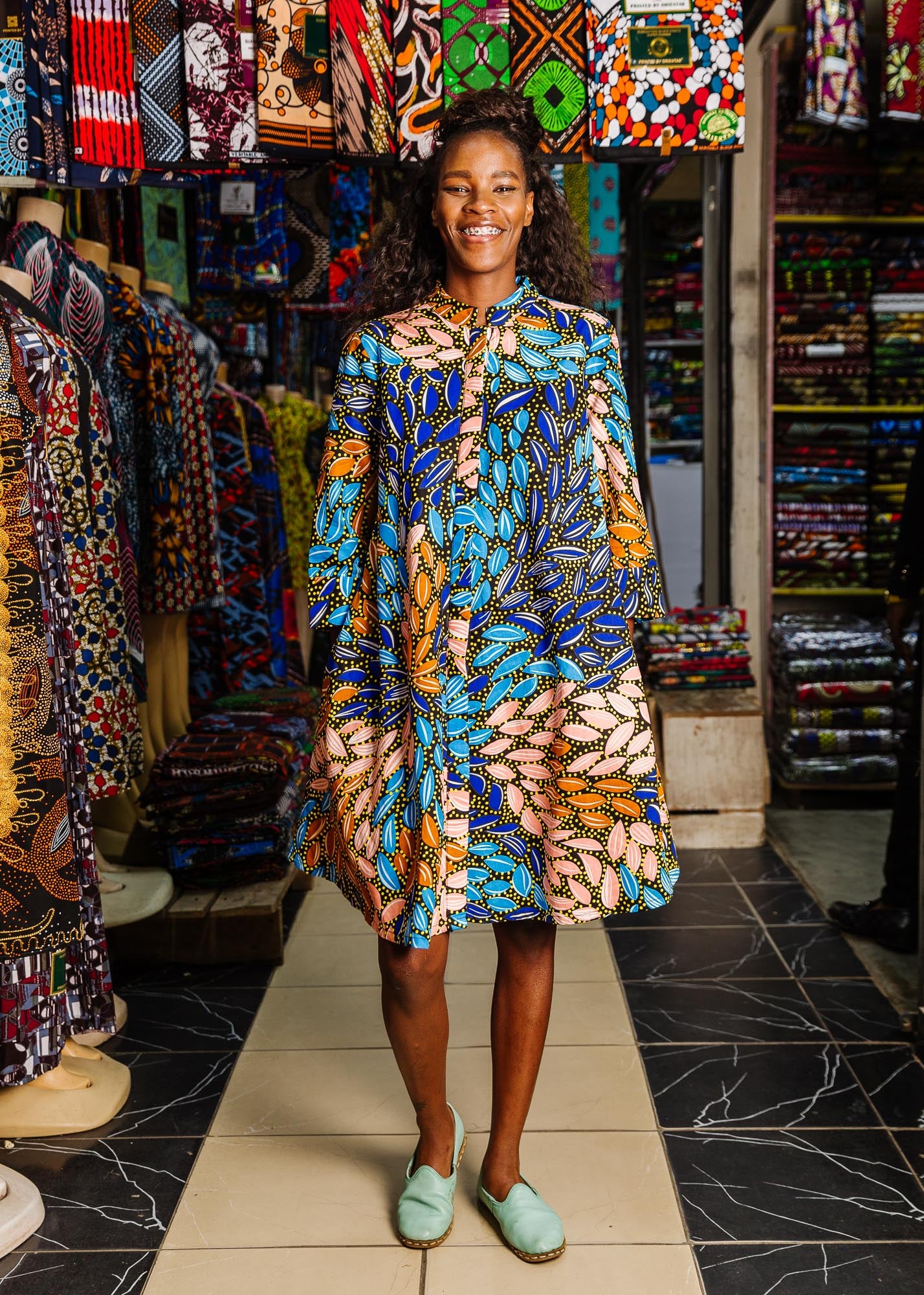 The model is wearing black dress with yellow dots and brown, blues, peach leaves.