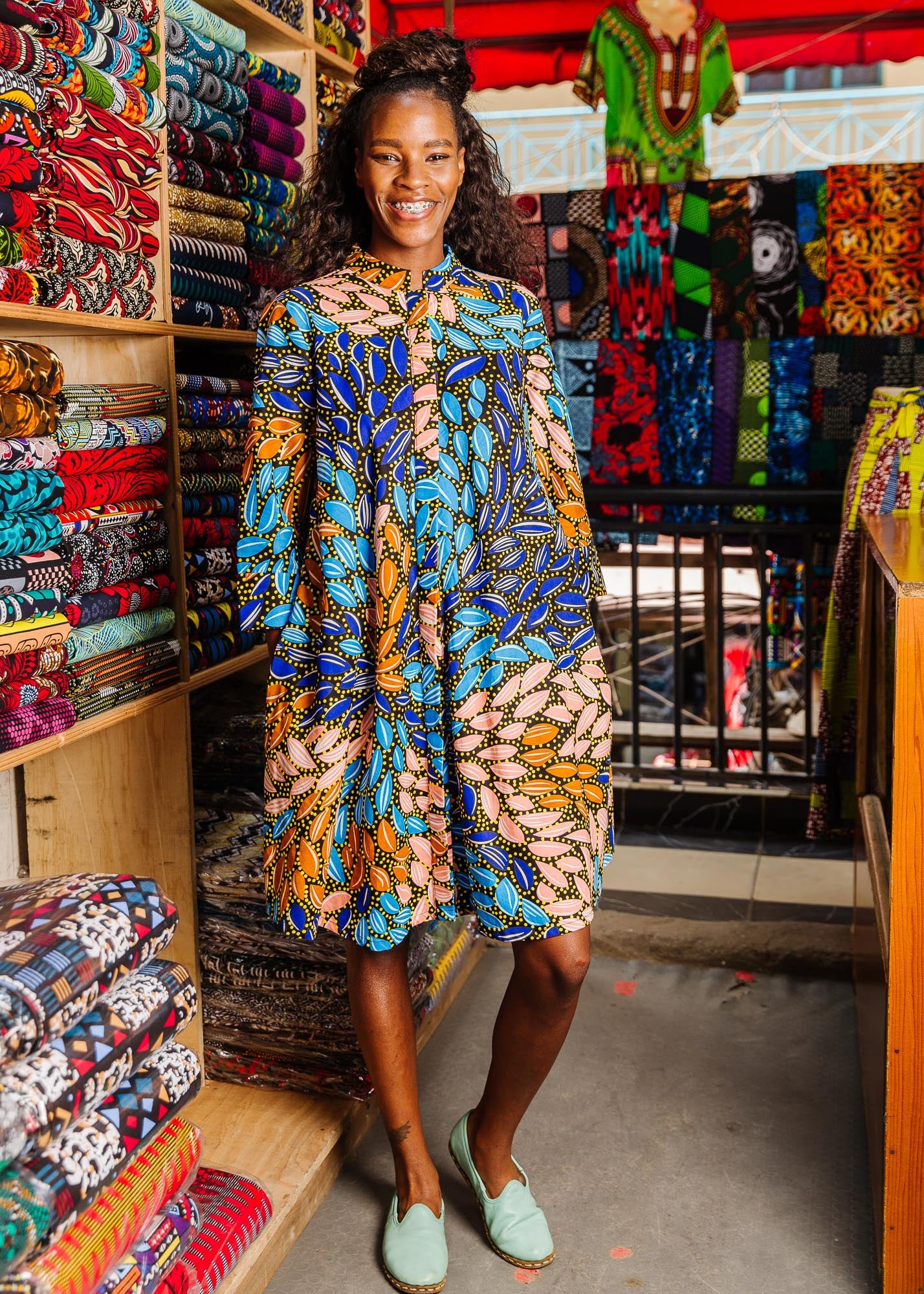 The model is wearing black dress with yellow dots and brown, blues, peach leaves.