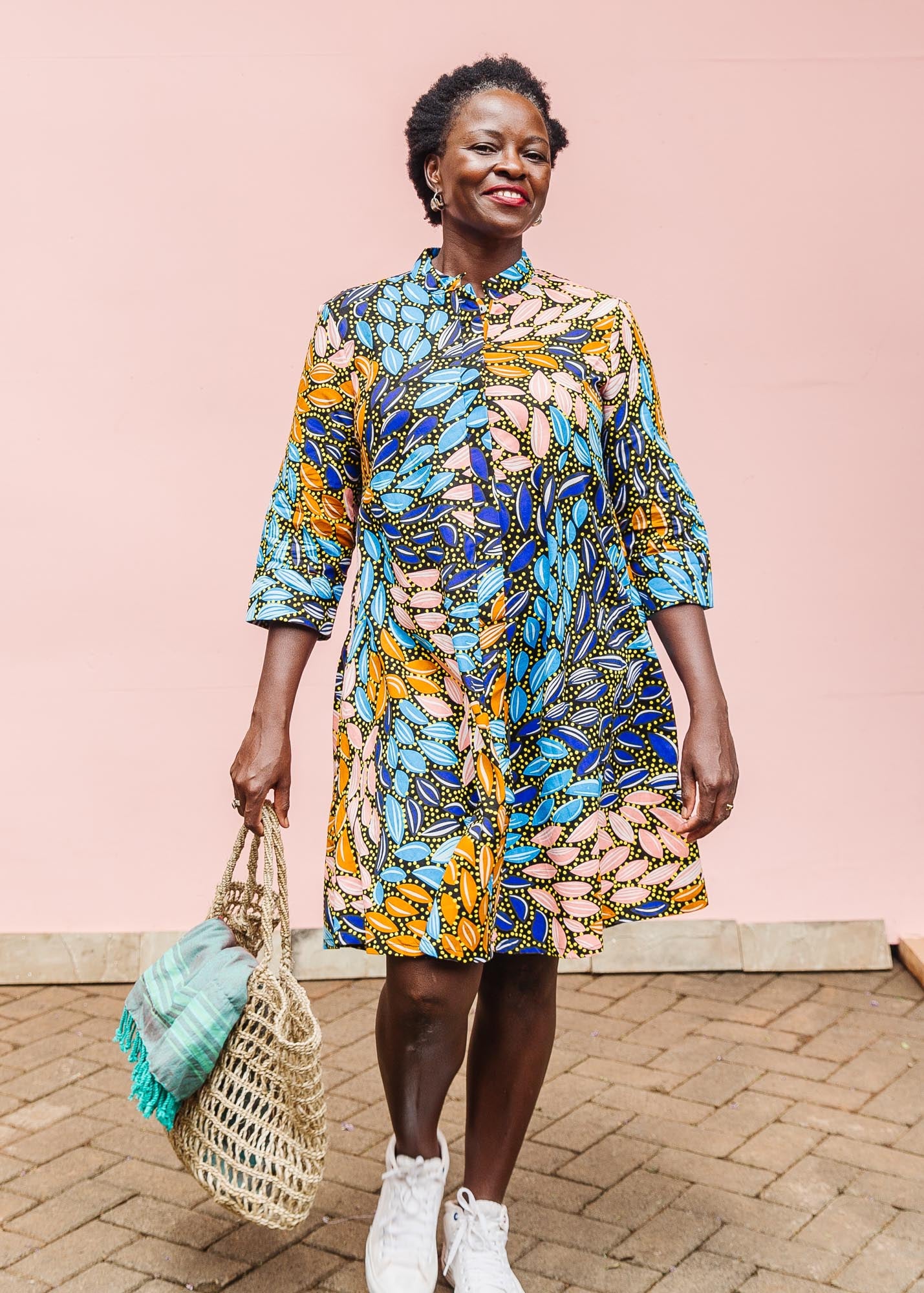 The model is wearing black dress with yellow dots and brown, blues, peach leaves.