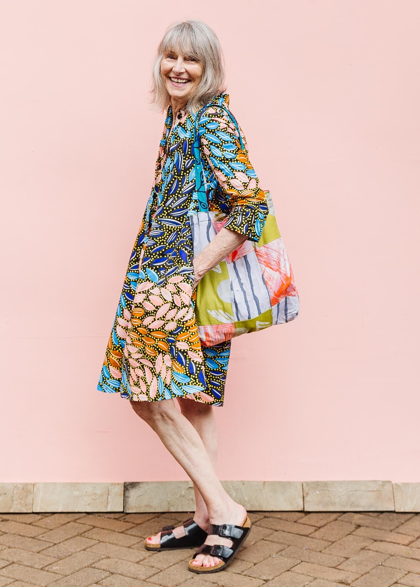 The model is wearing black dress with yellow dots and brown, blues, peach leaves.