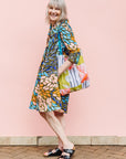 The model is wearing black dress with yellow dots and brown, blues, peach leaves.