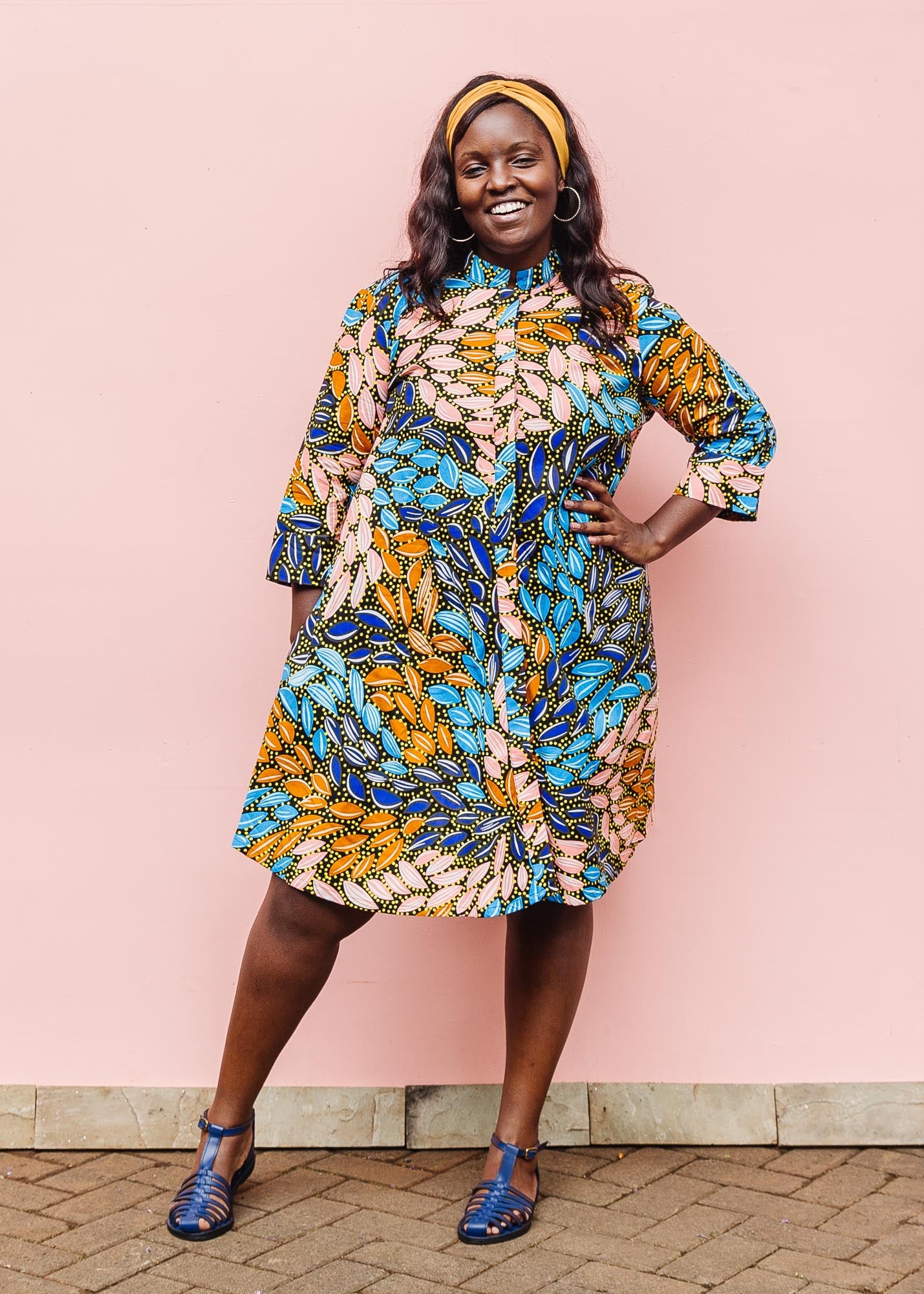 The model is wearing black dress with yellow dots and brown, blues, peach leaves.