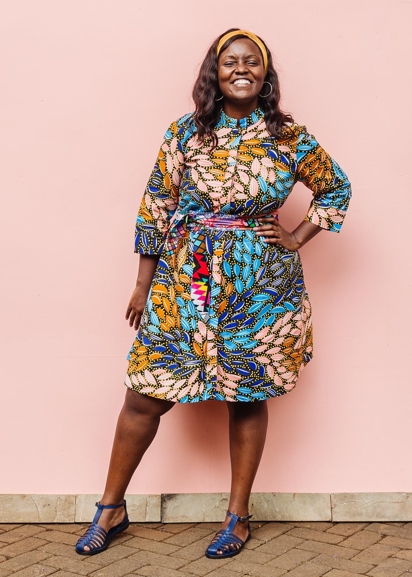 The model is wearing black dress with yellow dots and brown, blues, peach leaves.