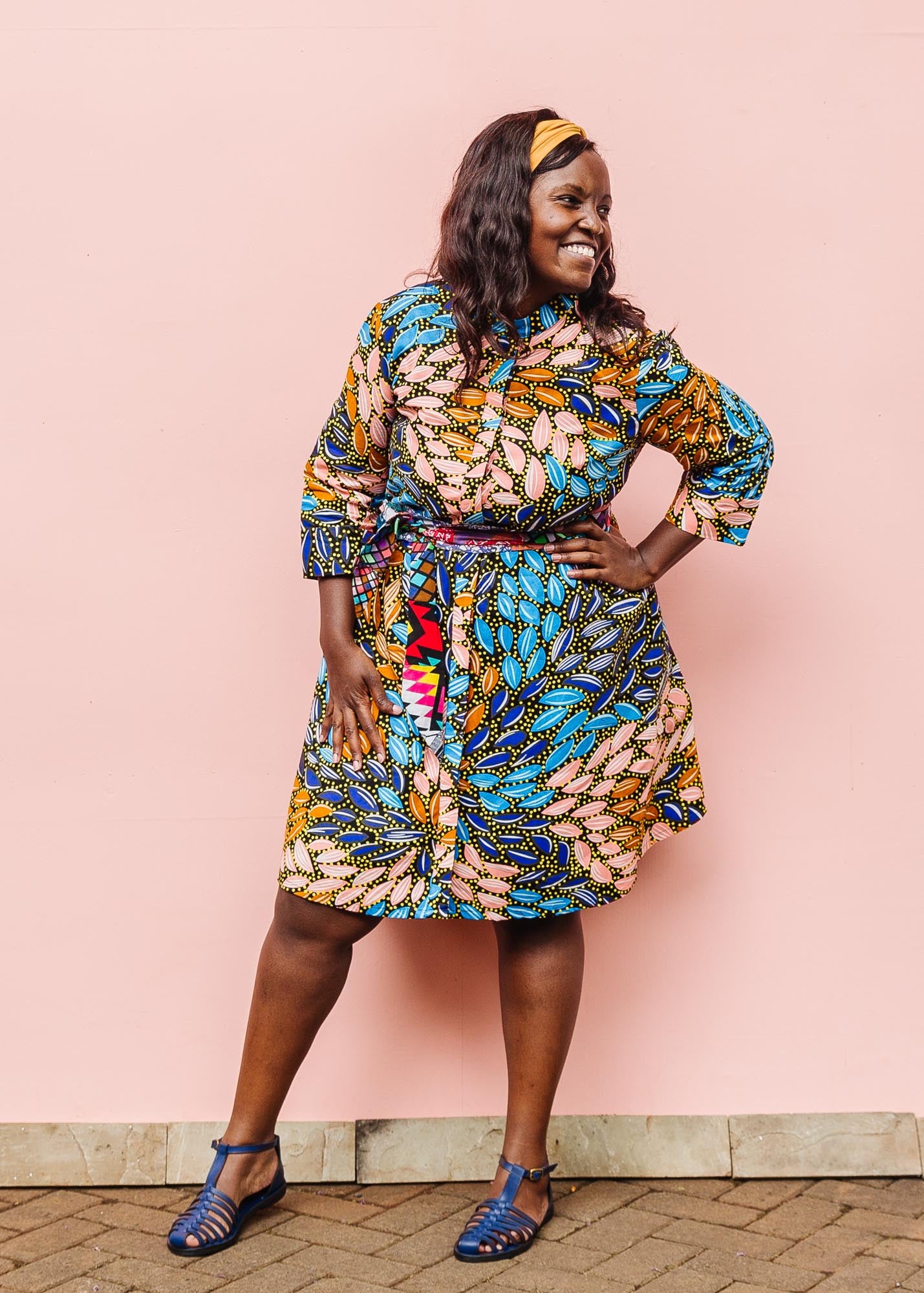 The model is wearing black dress with yellow dots and brown, blues, peach leaves.